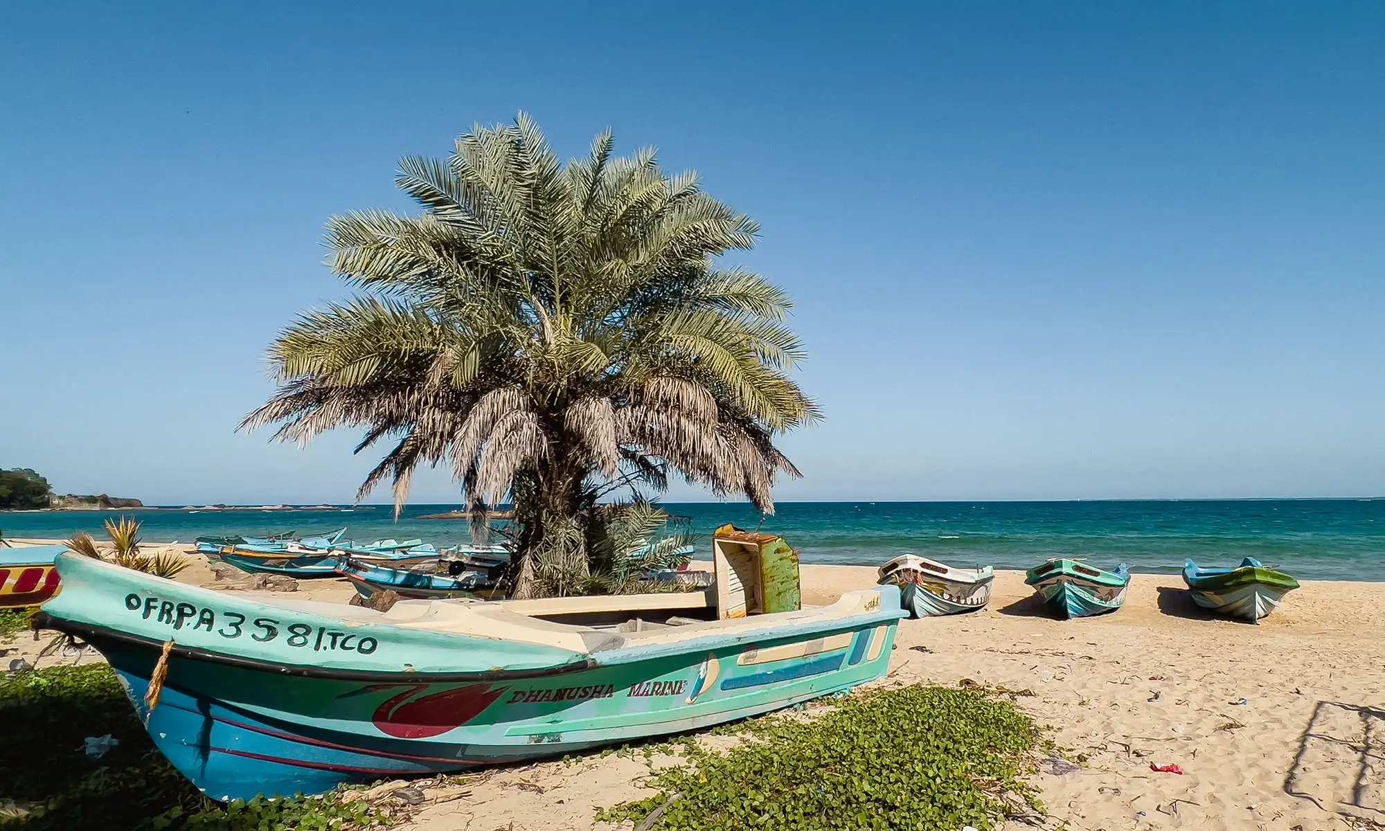 Boote auf einem weißen Sandstrand mit blauem Meer im Hintergrund